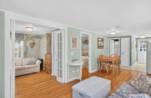 A spacious living area with a sofa, a dining table with chairs, a small side table, and a wicker ottoman.