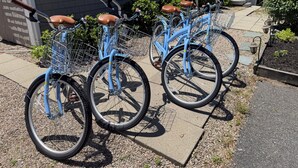 A row of blue bicycles with brown seats parked on a concrete path. - Relaxing Cape Cod Cottage Getaway (Dennis)