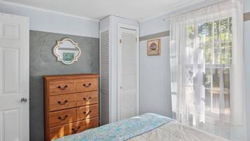 Quarto com cama, penteadeira, armário e janela com cortinas.