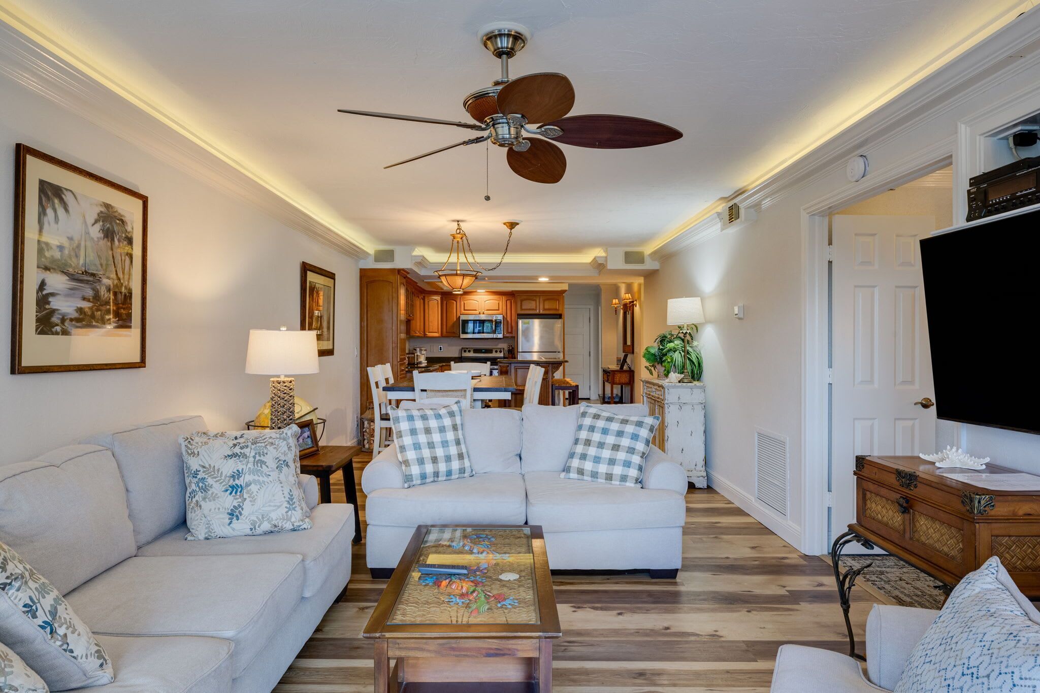 A living room with a ceiling fan, a sofa, a coffee table, and a television.
