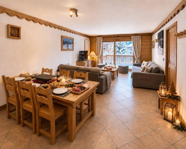 A cozy living area with a dining table set for a meal, a sofa, and a balcony with a view. - 20 meters from the ski slopes, 1st floor, sauna, patio, balcony, TV, 64 m², Peisey-Vallandry (Peisey-Nancroix)