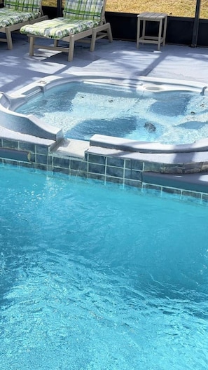 Ein Schwimmbecken mit Whirlpool, Liegestühlen und einem kleinen Tisch.