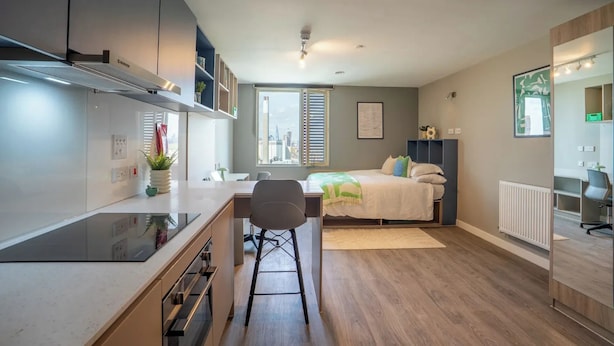Un appartement compact doté d’une kitchenette, d’un coin repas, d’un lit et offrant une vue sur le paysage urbain.