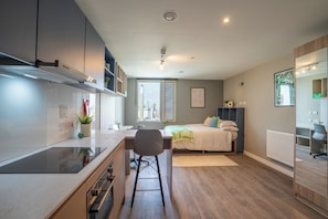 Eine moderne Wohnung mit Küche, Essbereich, Bett und großem Fenster mit Blick auf die Stadt.
