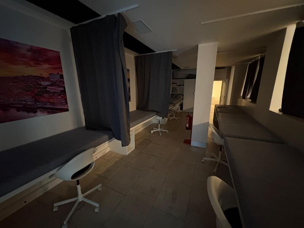 A room with a bed, a desk, a chair, a window, and a painting on the wall.