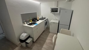 Una cocina funcional con lavadora, refrigerador y lavamanos.