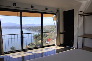 A room with a large window overlooking a body of water and a mountainous landscape.