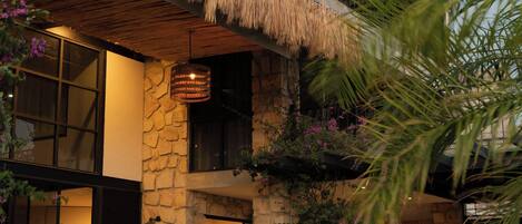 A two-story house with a stone facade, a thatched roof, and a balcony with a railing.