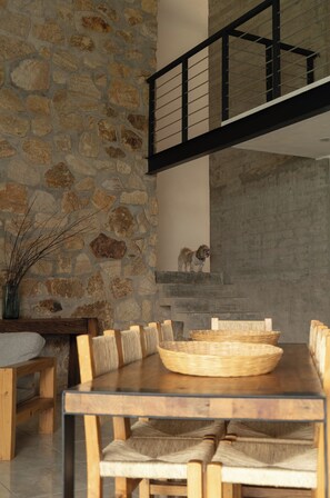 Un comedor con pared de piedra, muebles de madera y un perro en las escaleras.