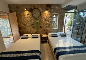 Quarto com duas camas, parede de pedra, mesa de cabeceira e janela com vista.