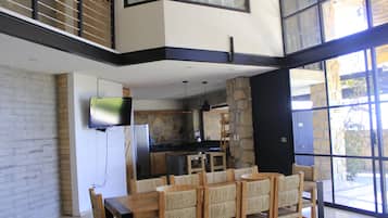 Una cocina moderna con salpicadero de piedra, un comedor con mesa y sillas de madera, y un televisor de pantalla plana montado en la pared.