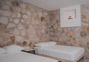 A room with a stone wall, two beds, a nightstand, and a framed picture on the wall. - Yauik Casa del Lago (Tequesquitengo)
