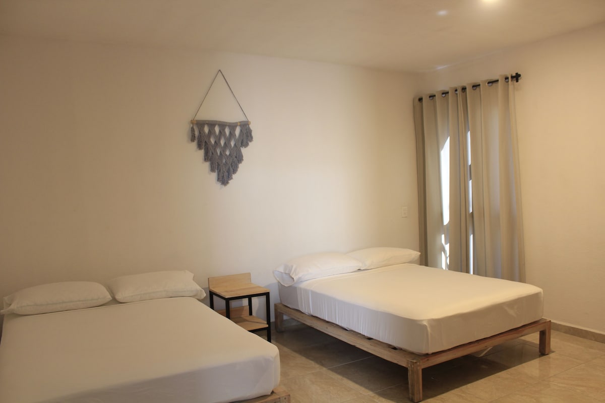 A hotel room with two beds, a small table, and a decorative wall hanging.