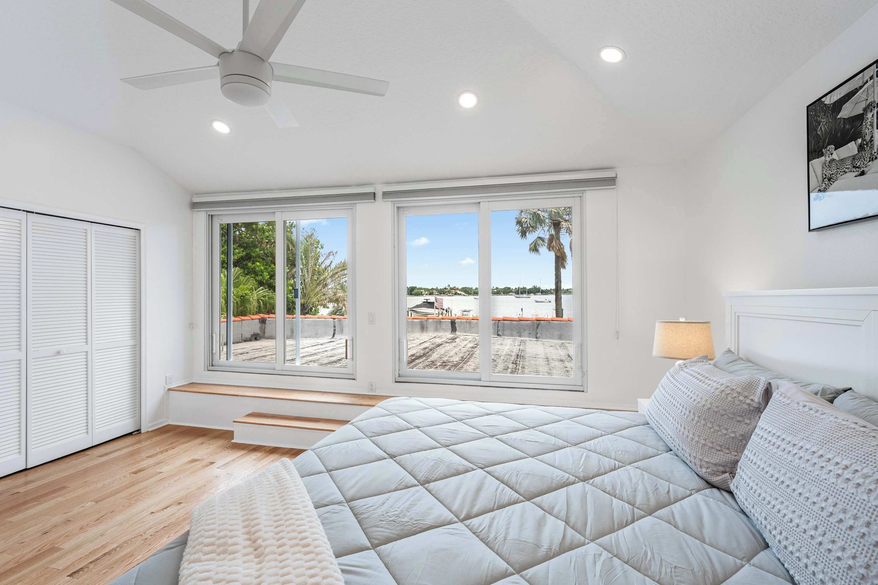 Ein Schlafzimmer mit einem großen Bett, einem Deckenventilator und Blick auf eine Dachterrasse.