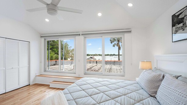Un dormitorio con una cama grande, un ventilador de techo y vistas a un patio en la azotea.