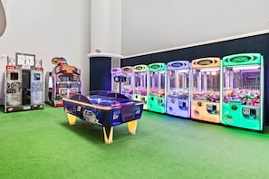 Una habitación con mesa de billar, juegos de arcade y máquinas de garra.