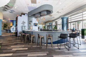 Eine moderne Bar mit einer gebogenen Theke, mehreren Hockstühlen und einer Wand mit Muster.