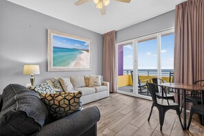 A living room with a sofa, a dining table, and a view of the ocean through a sliding glass door. - -New Listing- Breathtaking Direct Oceanfront Penthouse Suite (Daytona Beach)