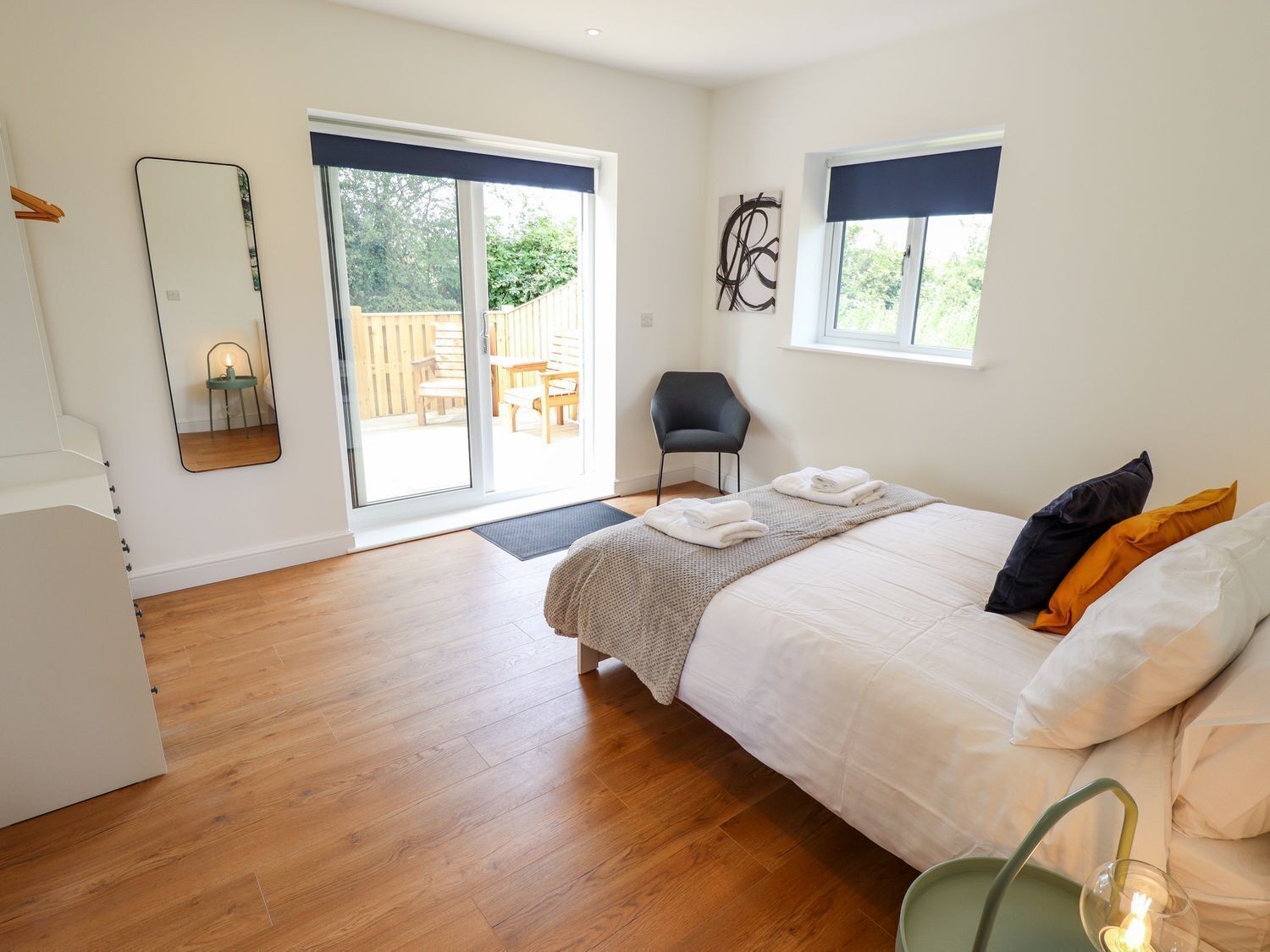 Quarto com cama, cadeira, um espelho grande e vista para área externa por uma porta de correr.