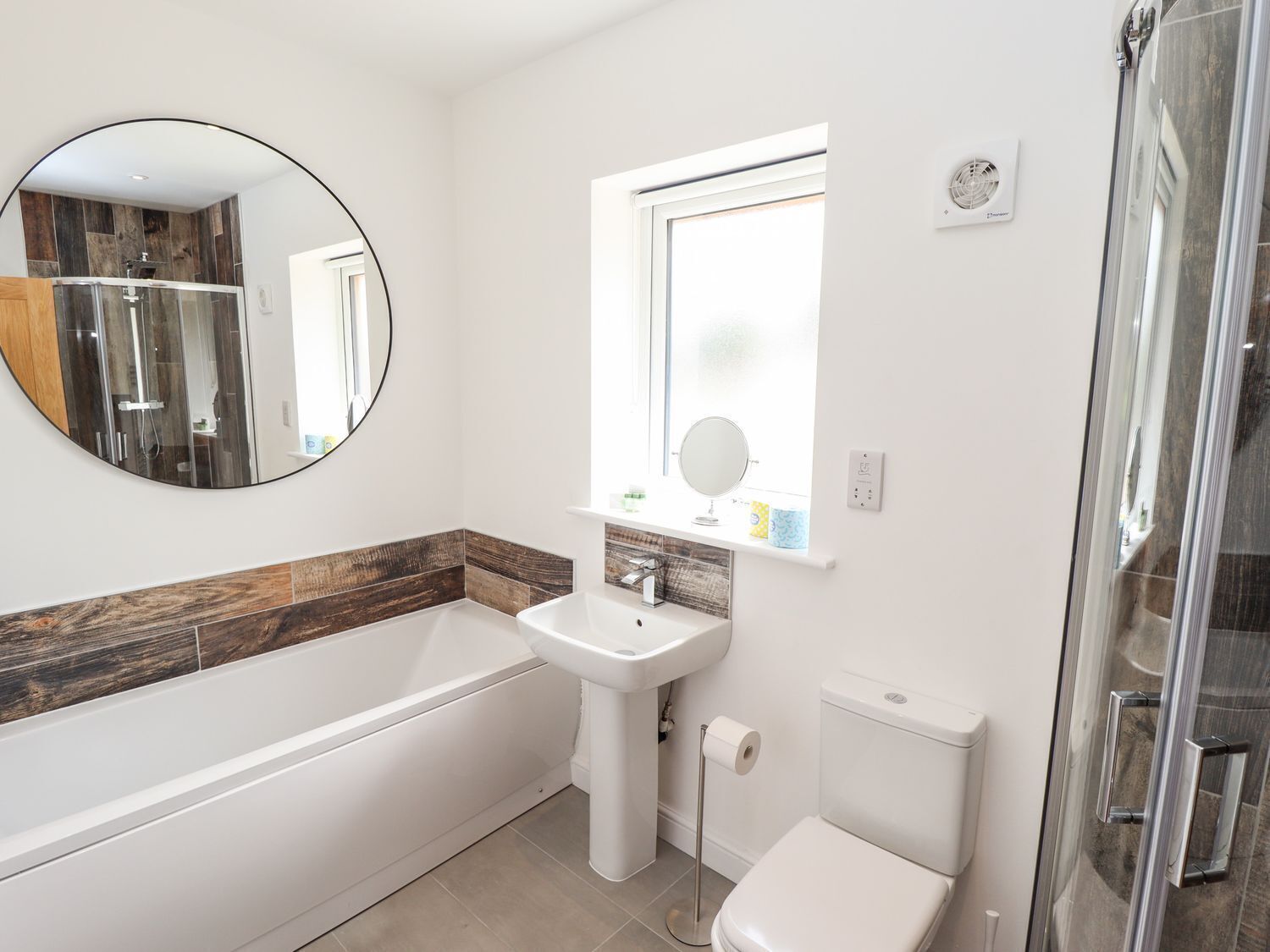 A modern bathroom with a bathtub, sink, toilet, and a glass shower enclosure.