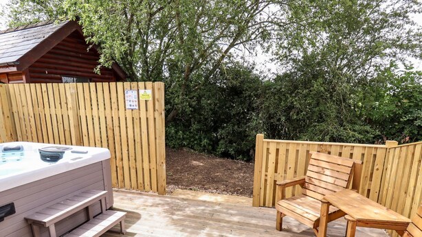 Una terraza de madera con un jacuzzi, un banco de madera y una mesa de madera.