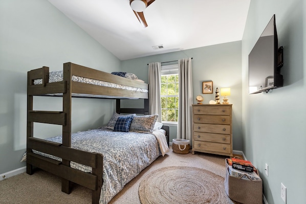 A bunk bed with a headboard, a dresser with drawers, a mirror, and a window with curtains.