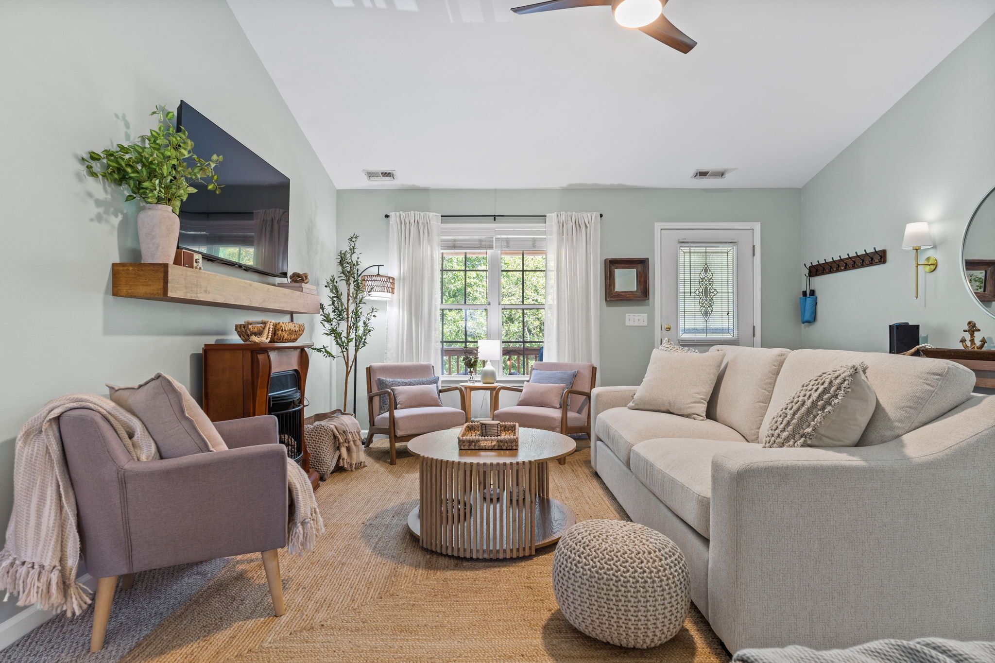 A living room with a sofa, chairs, a coffee table, a TV, and a plant.