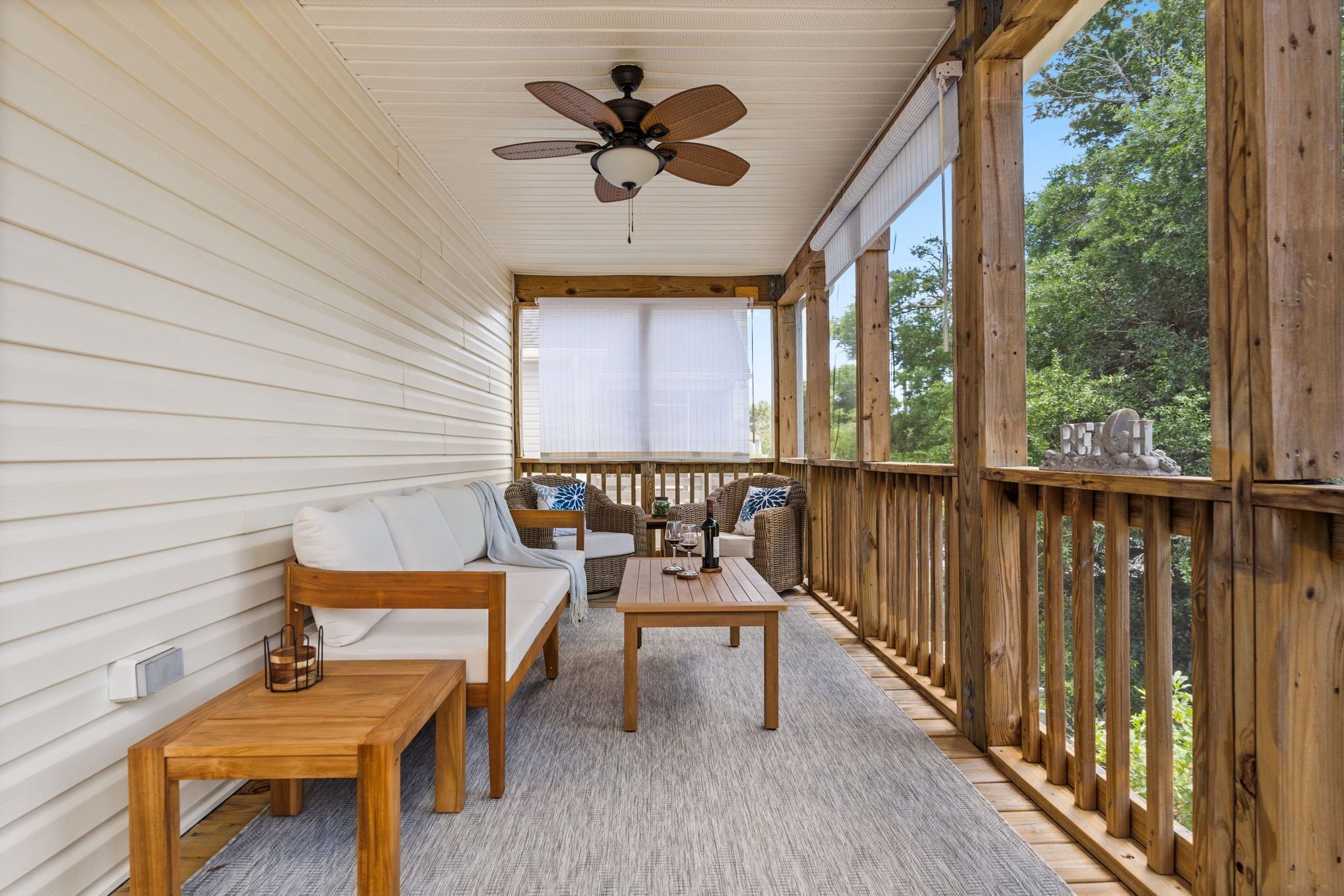 A covered porch with a ceiling fan, wooden furniture, and a view of the outdoors.