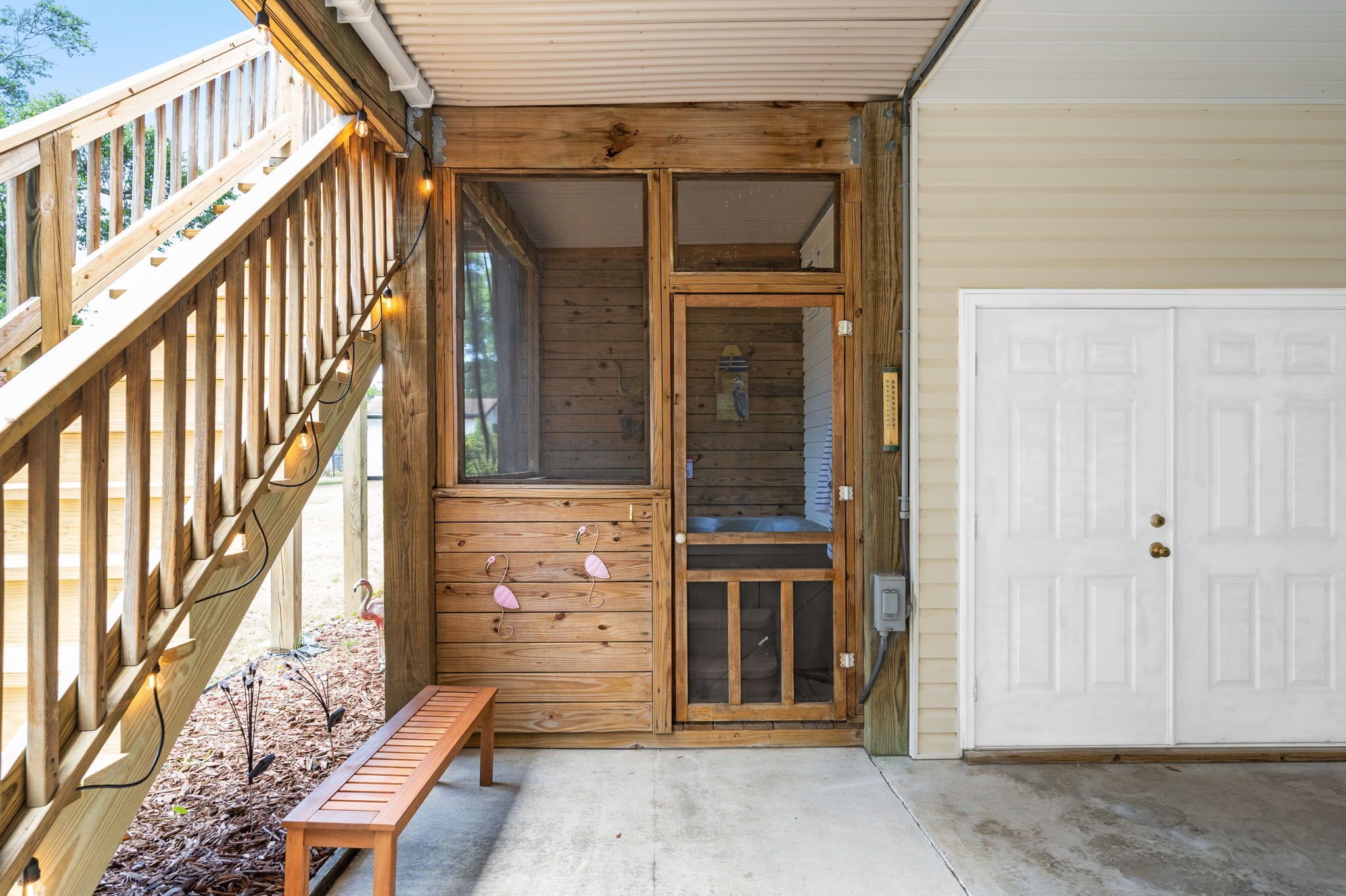 A wooden deck with a bench, a door, and a window.