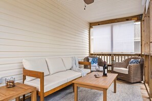 Ein gemütliches Zimmer mit einer Holzsofa, einem Holztisch, Korbstühlen und einem Fenster mit Jalousien.