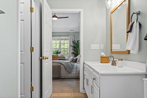 A bedroom with a bed, bedside table, and a window with curtains.