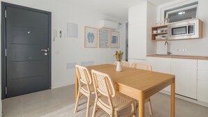 Une cuisine moderne équipée d’un four à micro-ondes, d’un évier et d’un coin repas avec une table en bois et des chaises en osier.