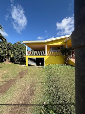 A yellow building with a covered entrance, a visible garage door, and a grassy yard.