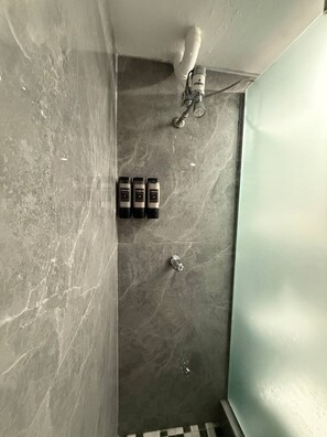 Ein Badezimmer mit Dusche, Handtuchhalter und Marmorwand.