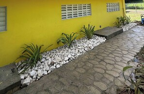 A yellow building with a stone pathway and white gravel borders. - Walk to the Beach · BioBay & Snorkel Tours (Vieques)