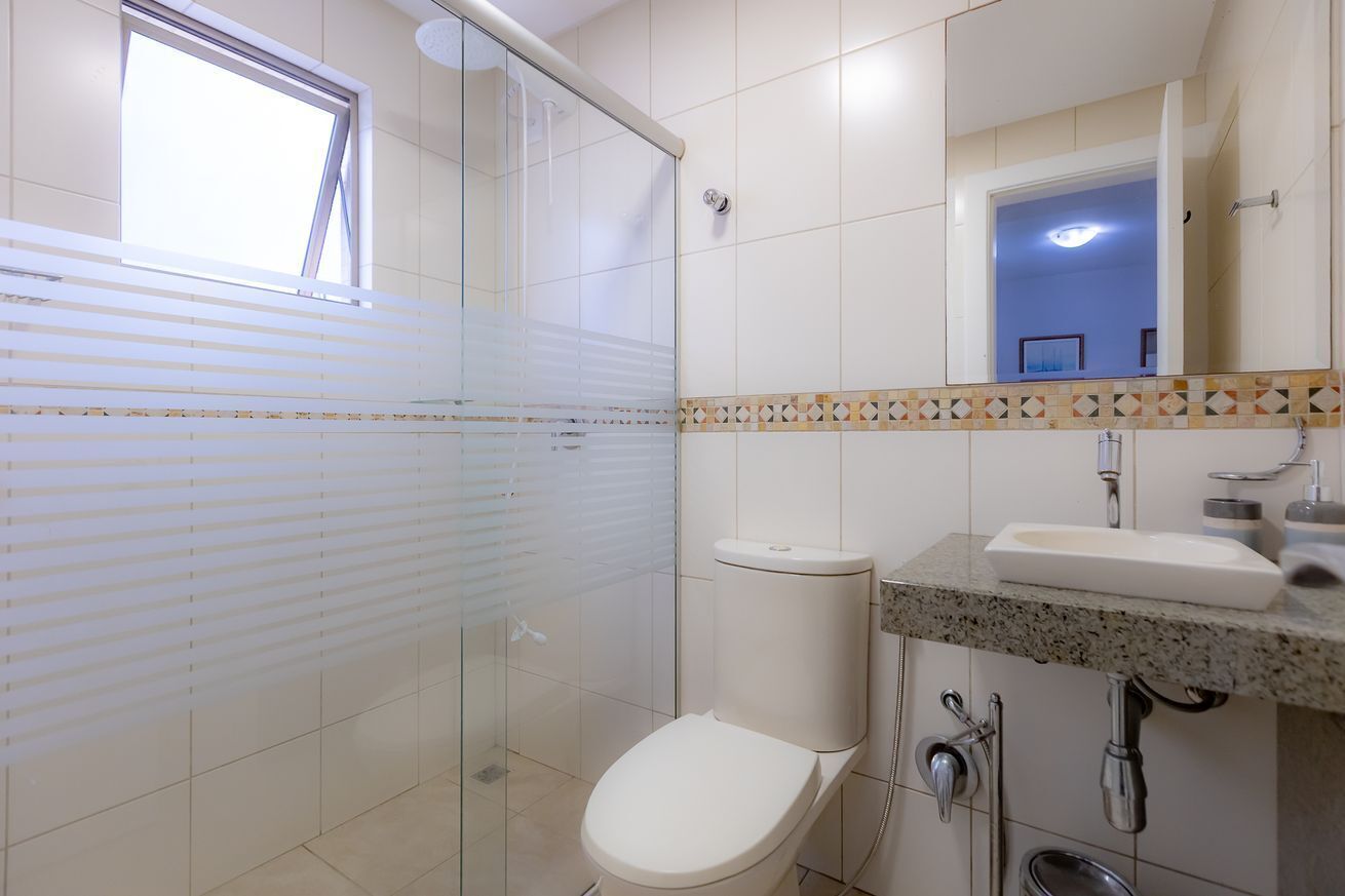 Ein Badezimmer mit Dusche, Toilette, Waschbecken und Spiegel.