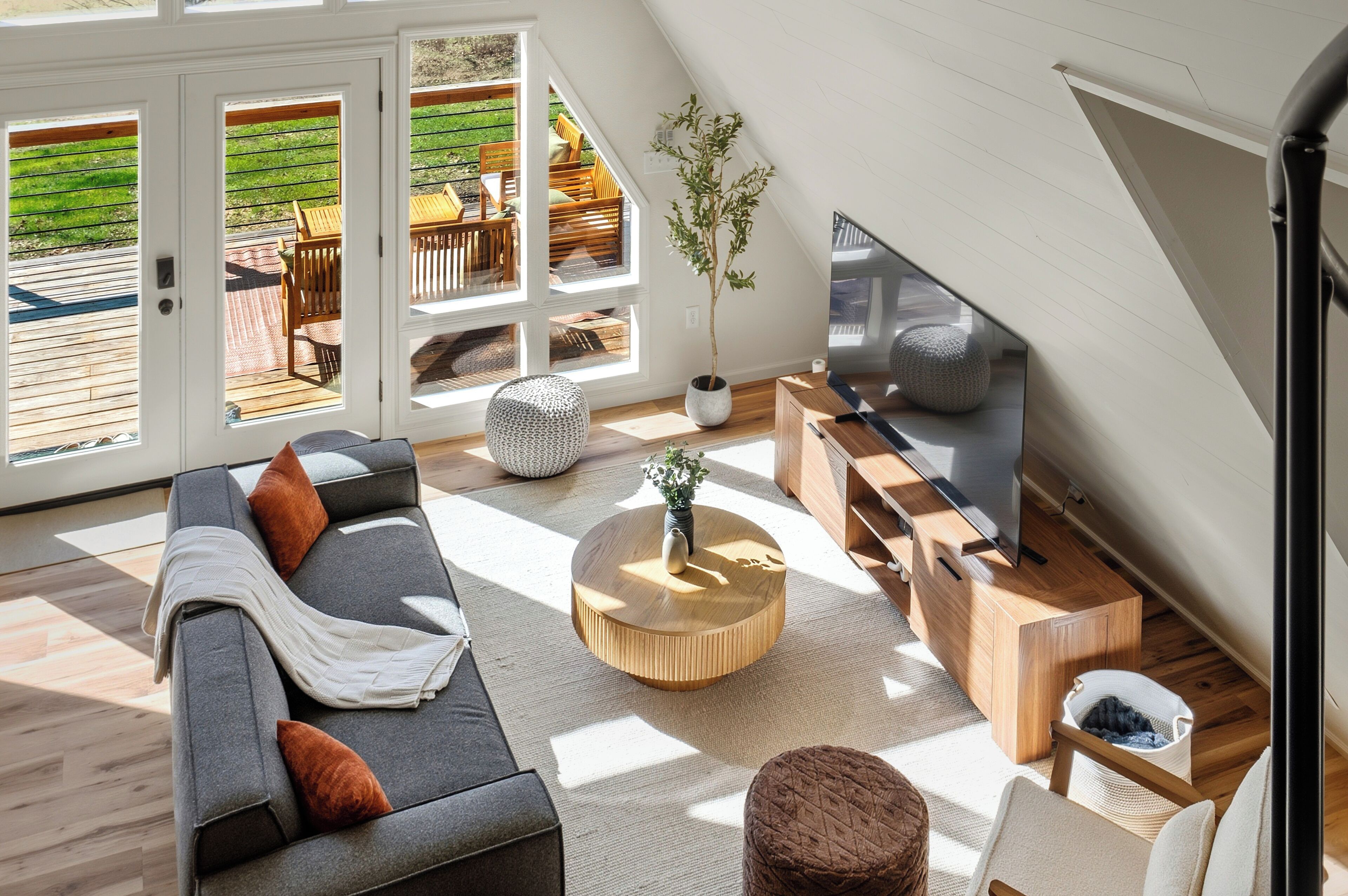 Una sala moderna con sofá, mesa de centro, televisor y vistas al exterior.