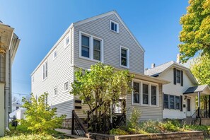A two-story house with a gabled roof, a front porch, and a small garden area. - Whole Contemporary House in Bay View (Milwaukee)