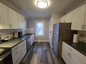 A kitchen with white cabinets, a coffee bar, and a window with blinds. - Whole Contemporary House in Bay View (Milwaukee)