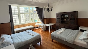 Habitación de hotel con dos camas, un escritorio, una silla, una araña y vistas al exterior.