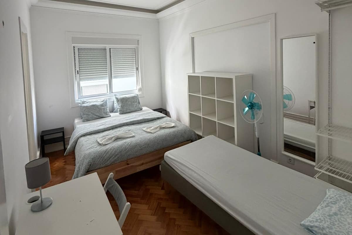 A bedroom with a bed, a desk, a chair, a wardrobe, and a window.