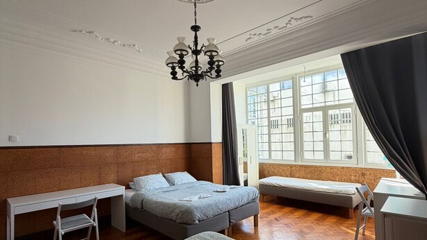 Habitación de hotel con una cama grande, un escritorio, una silla, una mesita y una ventana con cortinas.