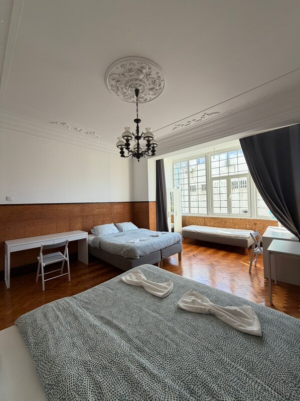 A hotel room with a large bed, a desk, a chair, a small table, and a window with curtains. - Don Alvares (Lisbon)