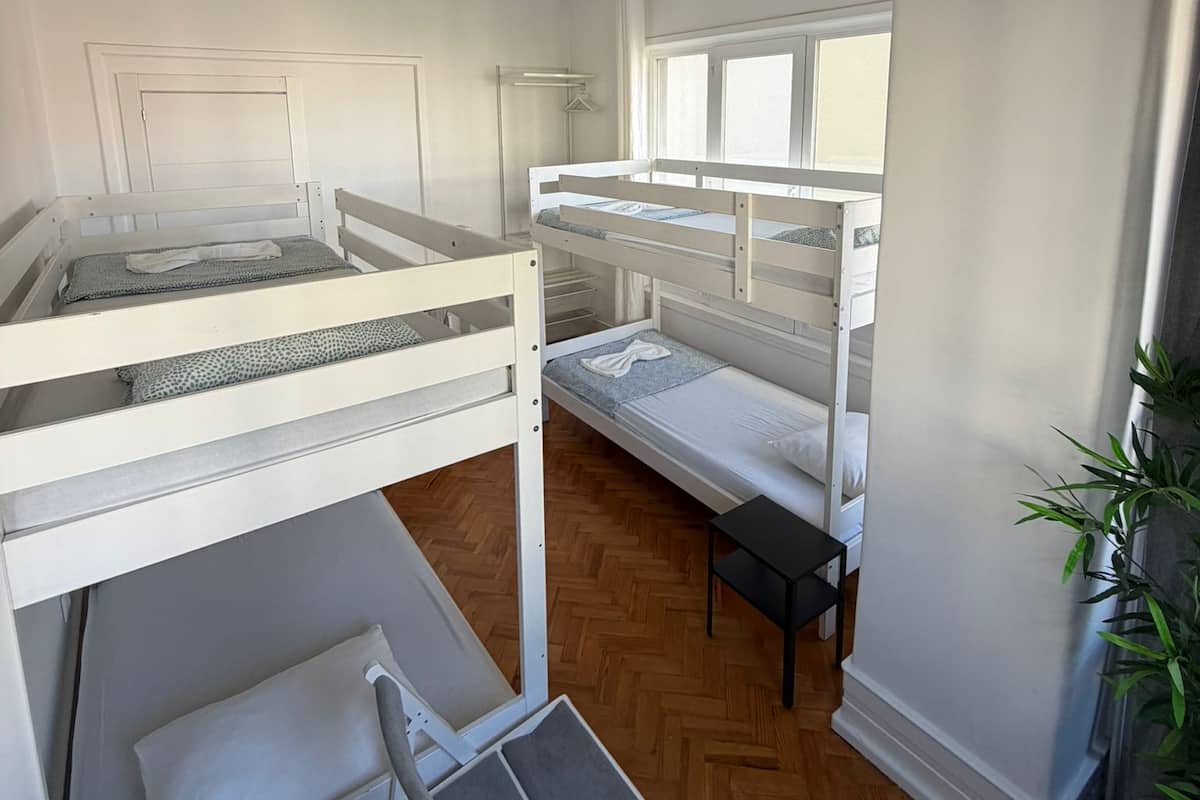 A room with bunk beds, a small table, and a window.