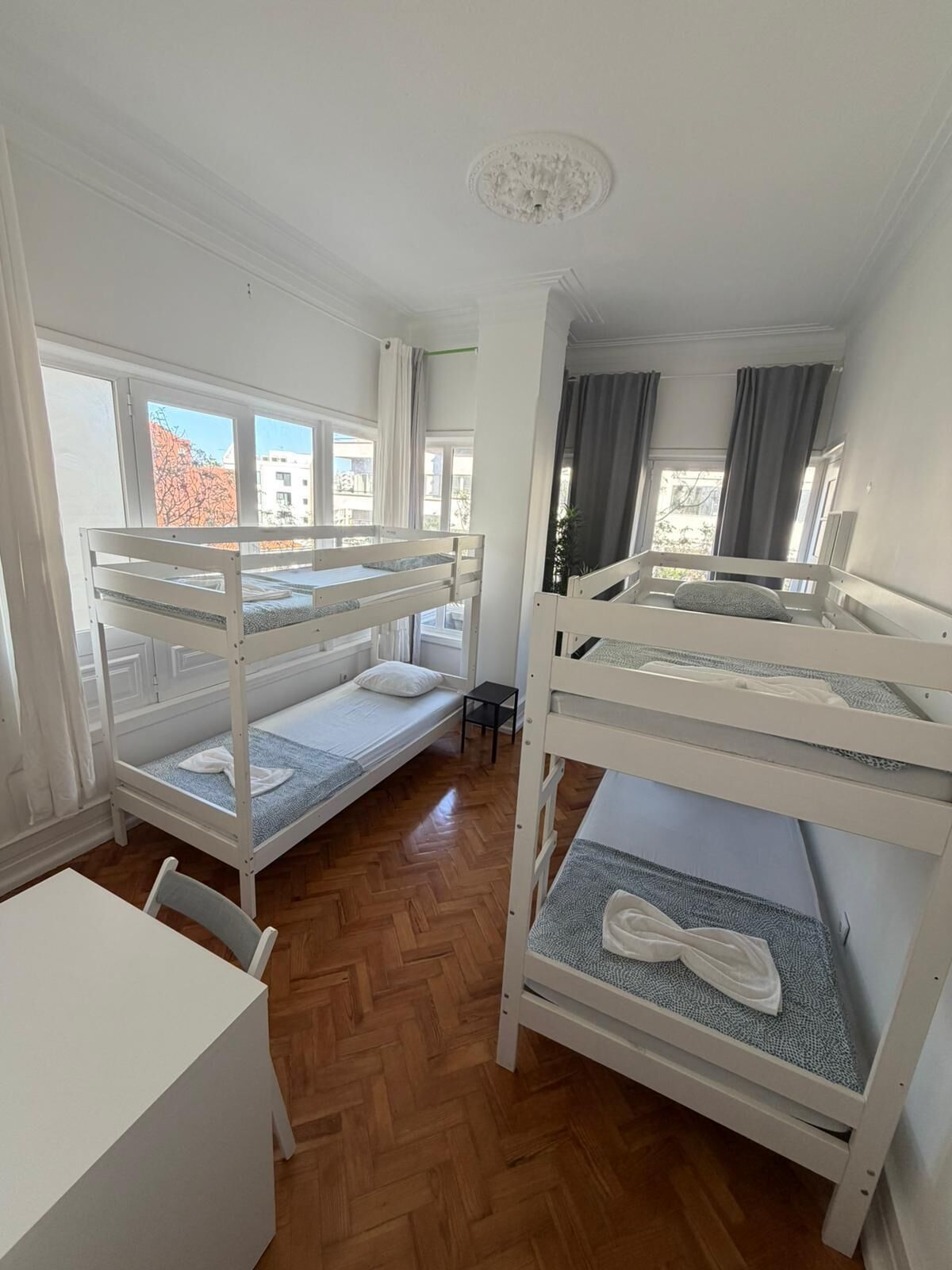 A dormitory room with bunk beds, a small table, and a chair.