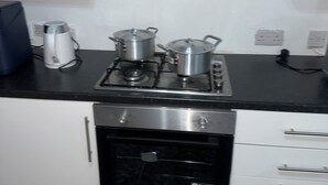 Una cocina con estufa, ollas, hervidor y lavavajillas.