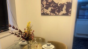 Un comedor con mesa de vidrio, sillas y un florero.