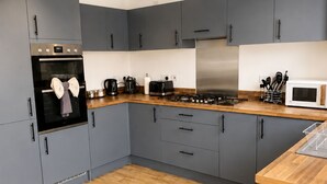 Una cucina moderna con pensili grigi, un piano di lavoro in legno, un frigorifero in acciaio inossidabile e un forno integrato.