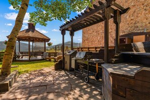 Eine Außenpatio mit Grill, Sitzgelegenheiten und einer Pergola.