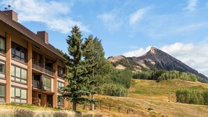 A two-story building with a balcony, a mountain in the background, and a clear sky. - Columbine 2308 (Crested Butte)